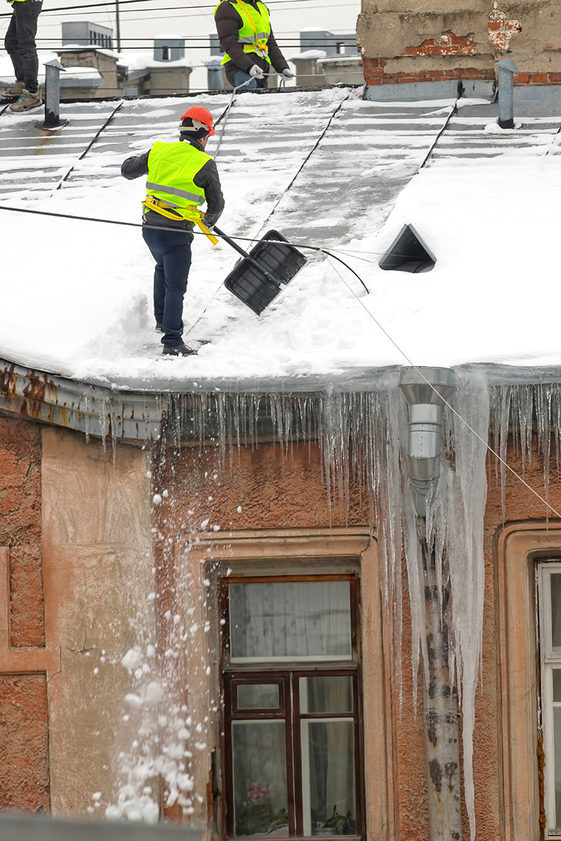 Déneigement manuel d'un toit commercial.