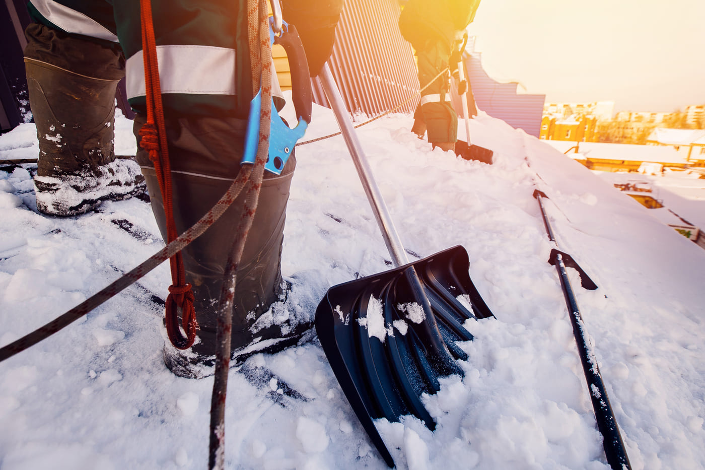 Équipe qui déneige manuellement un toit.
